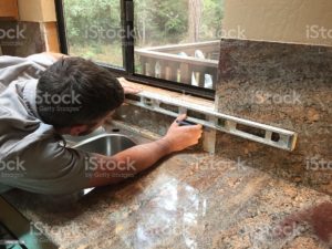 Remodeling home with granite counter tops. Man leveling counter top.